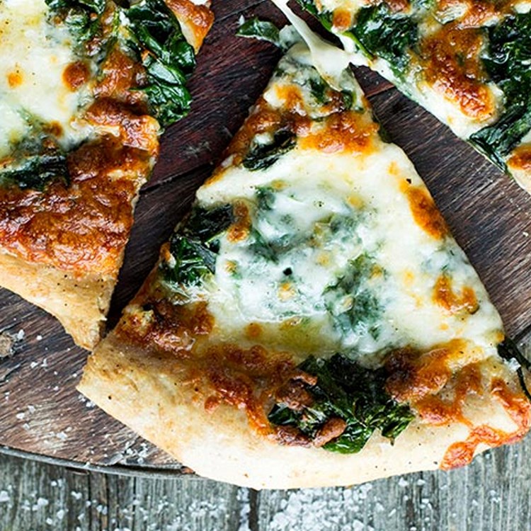 Hvit pizza på grov bunn med spinat og bakt hvitløk