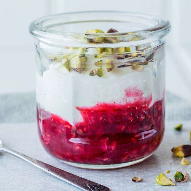 Yoghurt og rørte bringebær med pistasjnøtter