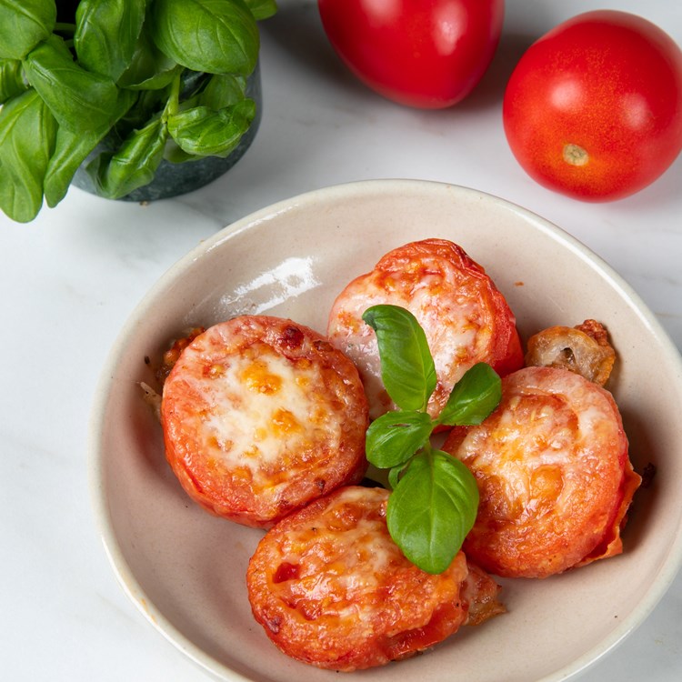 Bilde av tomat i en skål. Tomatene er laget i airfryer, og de har mozarellaost på toppen.