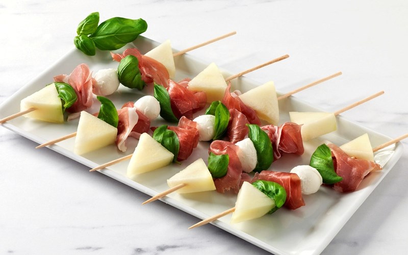 Melonspyd med serranoskinke, mozzarella og basilikum.
